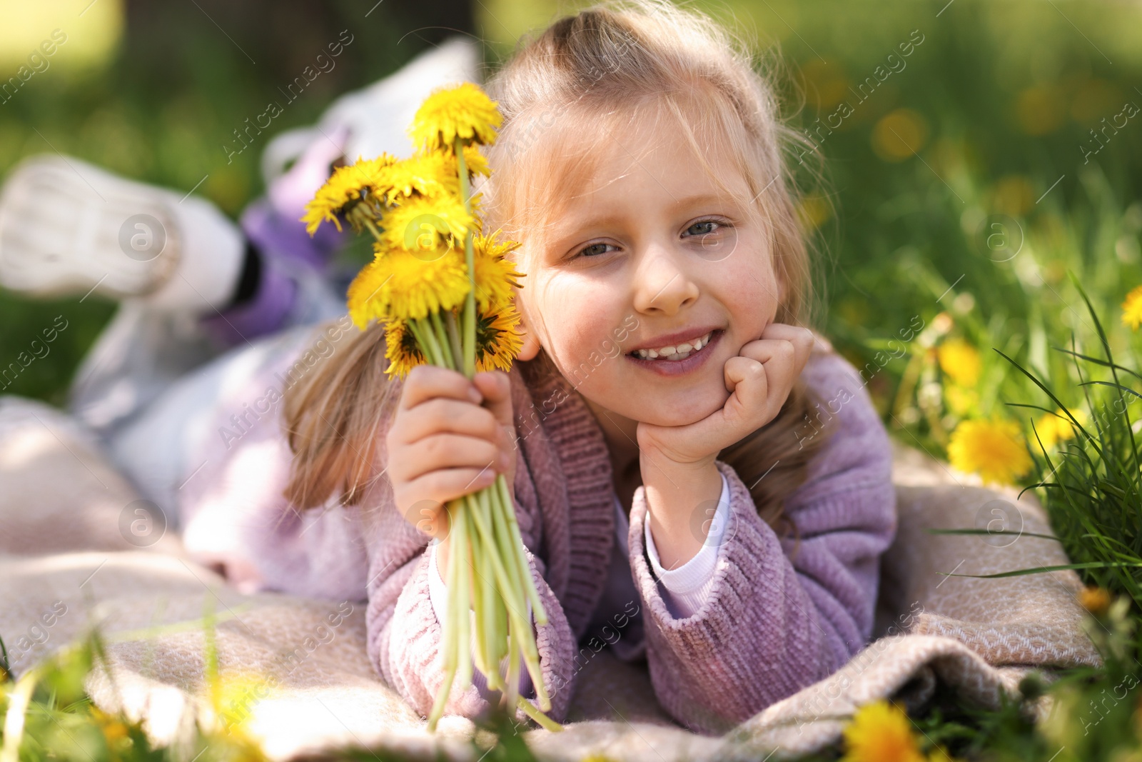 Cute little girl with beautiful dandelions on green grass outdoors Photo of Cute little girl with beautiful dandelions on green grass outdoors