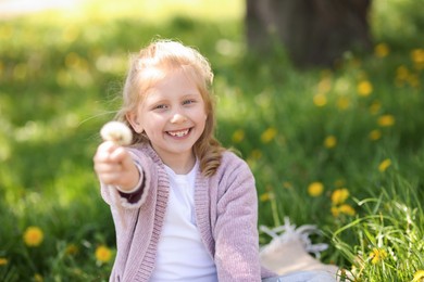 Photo of Cute little girl with beautiful dandelion outdoors, space for text