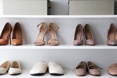 Photo of Different footwear on shelves indoors. Shoe storage