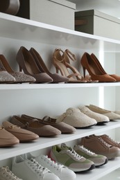 Photo of Different footwear on shelves indoors, closeup. Shoe storage