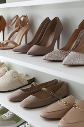 Photo of Different footwear on shelves indoors, closeup. Shoe storage