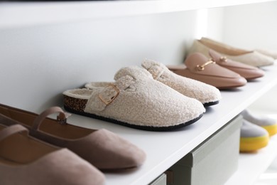 Photo of Different footwear on shelf indoors, closeup. Shoe storage