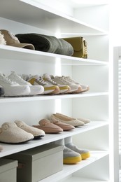 Photo of Different footwear, clothes and accessories on shelves indoors, closeup. Shoe storage