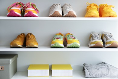 Photo of Different footwear and clothes on shelves indoors. Shoe storage