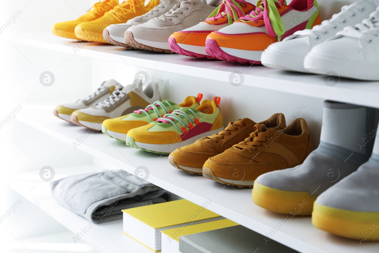 Different footwear and clothes on shelves indoors, closeup. Shoe storage Photo of Different footwear and clothes on shelves indoors, closeup. Shoe storage