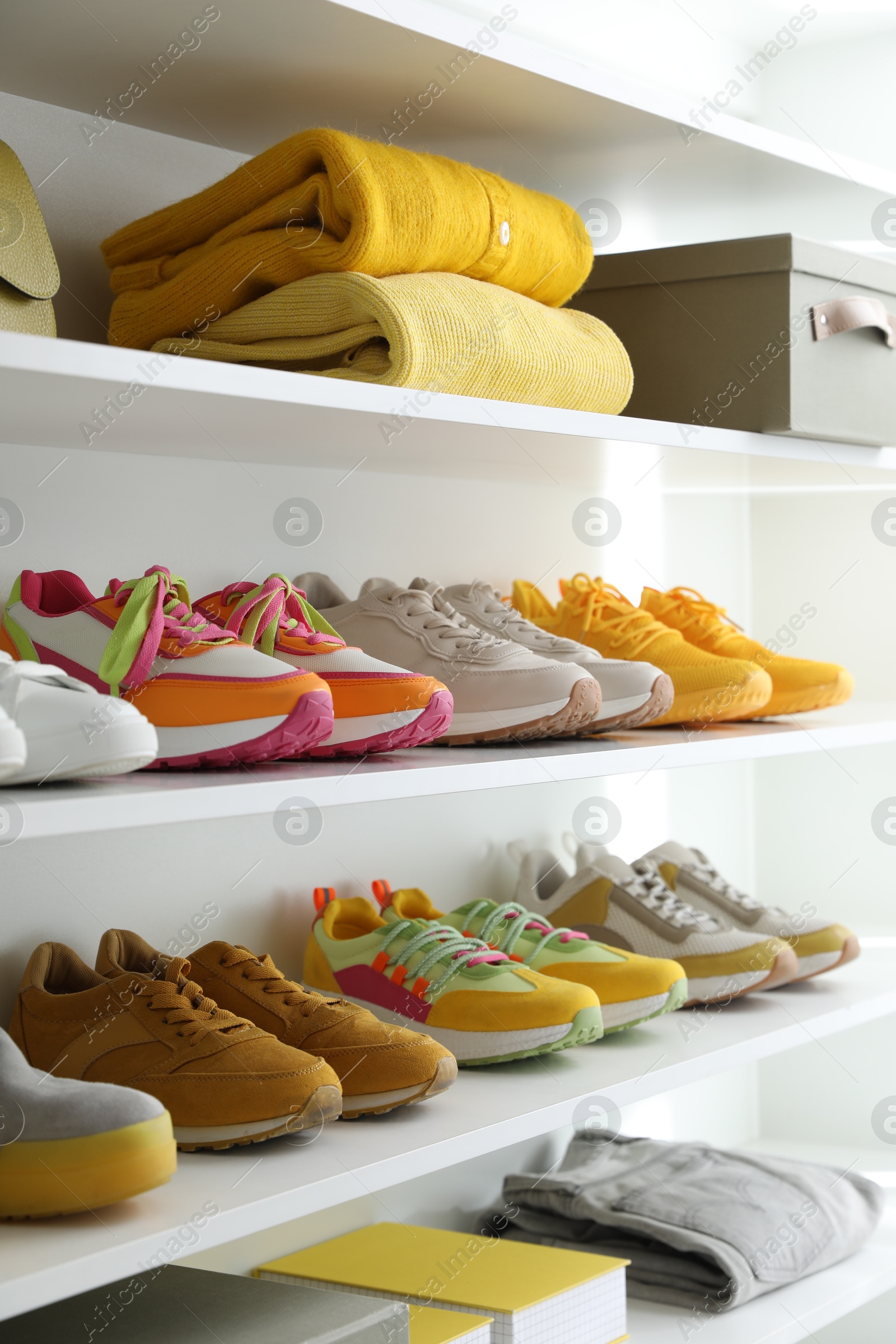 Different footwear and clothes on shelves indoors, closeup. Shoe storage Photo of Different footwear and clothes on shelves indoors, closeup. Shoe storage