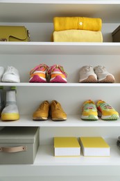 Photo of Different footwear, clothes and bag on shelves indoors. Shoe storage