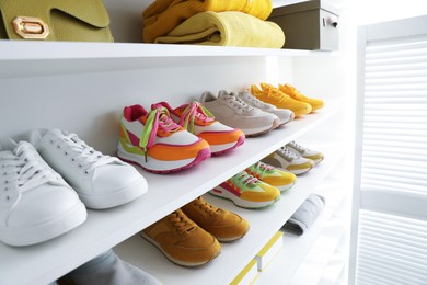 Photo of Different footwear, clothes and bag on shelves indoors, closeup. Shoe storage