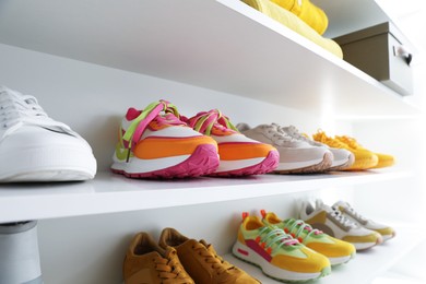 Photo of Different footwear on shelves indoors, closeup. Shoe storage