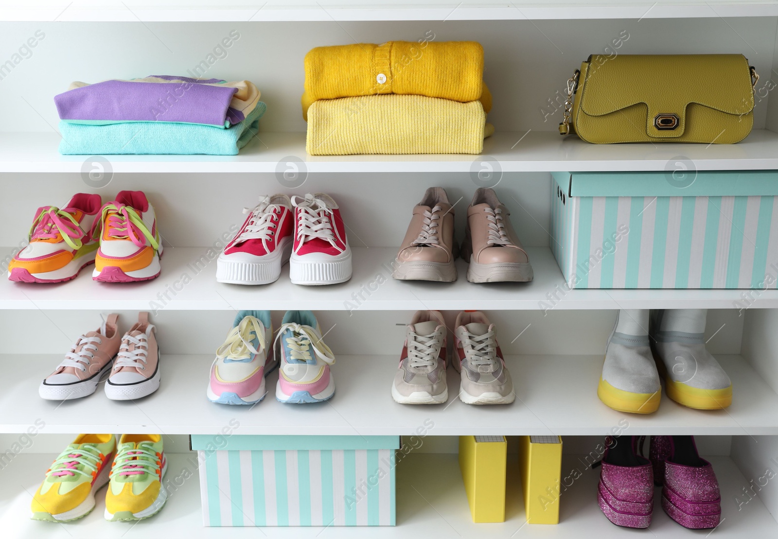 Photo of Different footwear, clothes and bag on shelves indoors. Shoe storage