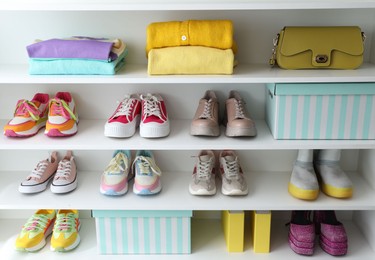 Photo of Different footwear, clothes and bag on shelves indoors. Shoe storage