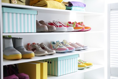 Photo of Different footwear and clothes on shelves indoors, closeup. Shoe storage