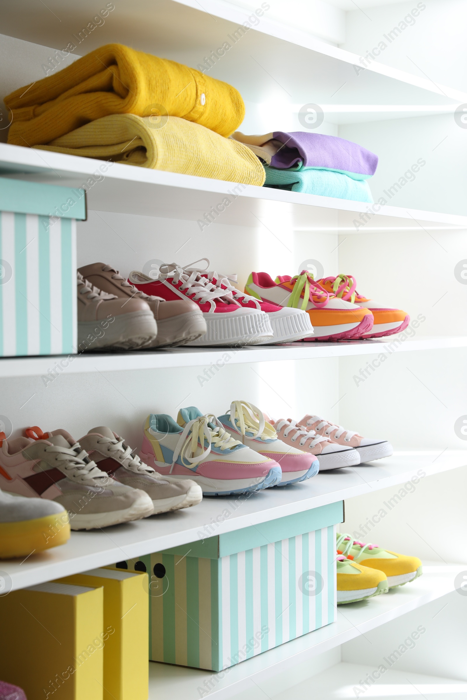Different footwear and clothes on shelves indoors, closeup. Shoe storage Photo of Different footwear and clothes on shelves indoors, closeup. Shoe storage