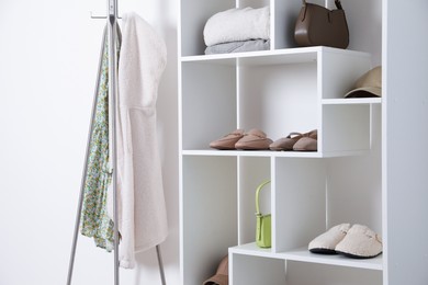 Photo of Shelving unit with different footwear, clothes and accessories indoors. Shoe storage