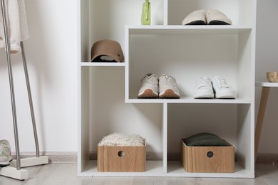 Photo of Shelving unit with different footwear, clothes and accessories indoors. Shoe storage