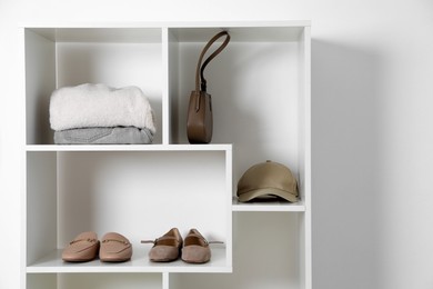 Photo of Shelving unit with different footwear and accessories indoors. Shoe storage