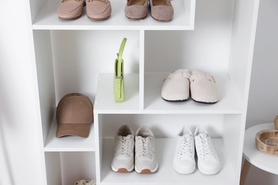 Photo of Shelving unit with different footwear and accessories indoors. Shoe storage