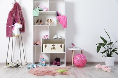Photo of Shelving unit with different footwear, accessories and clothes indoors. Shoe storage