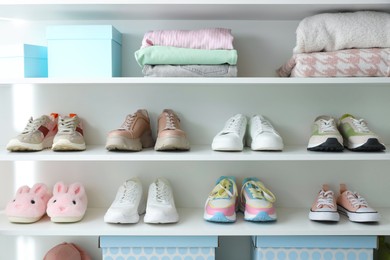 Photo of Different footwear and clothes on shelves indoors. Shoe storage