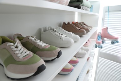 Photo of Different footwear on shelves indoors, closeup. Shoe storage