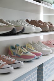 Photo of Different footwear on shelves indoors, closeup. Shoe storage