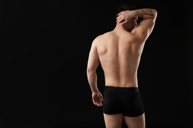Photo of Young man in stylish underwear on black background, back view. Space for text