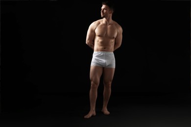 Photo of Young man in stylish white underwear on black background