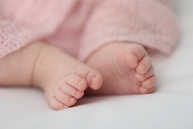 Photo of Little baby lying on bed indoors, closeup