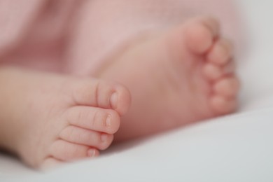 Photo of Little baby lying on bed indoors, closeup