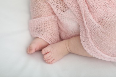 Photo of Little baby lying on bed indoors, closeup