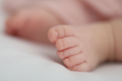 Photo of Little baby lying on bed indoors, closeup