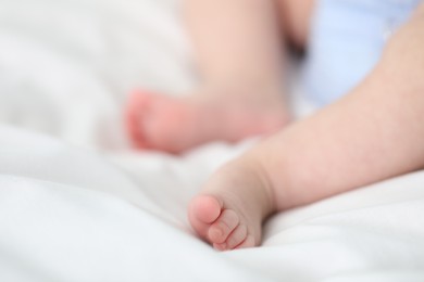 Photo of Little baby lying on bed indoors, closeup