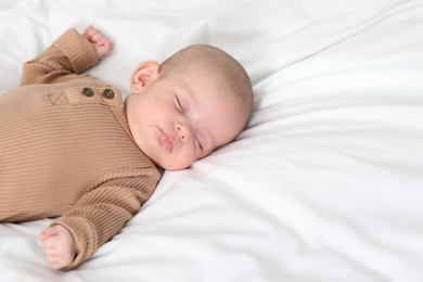 Photo of Cute little baby sleeping on bed indoors, space for text
