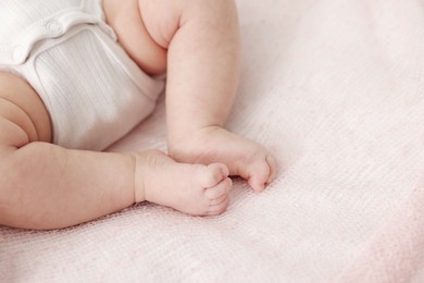 Photo of Cute little baby lying on bed at home, closeup. Space for text