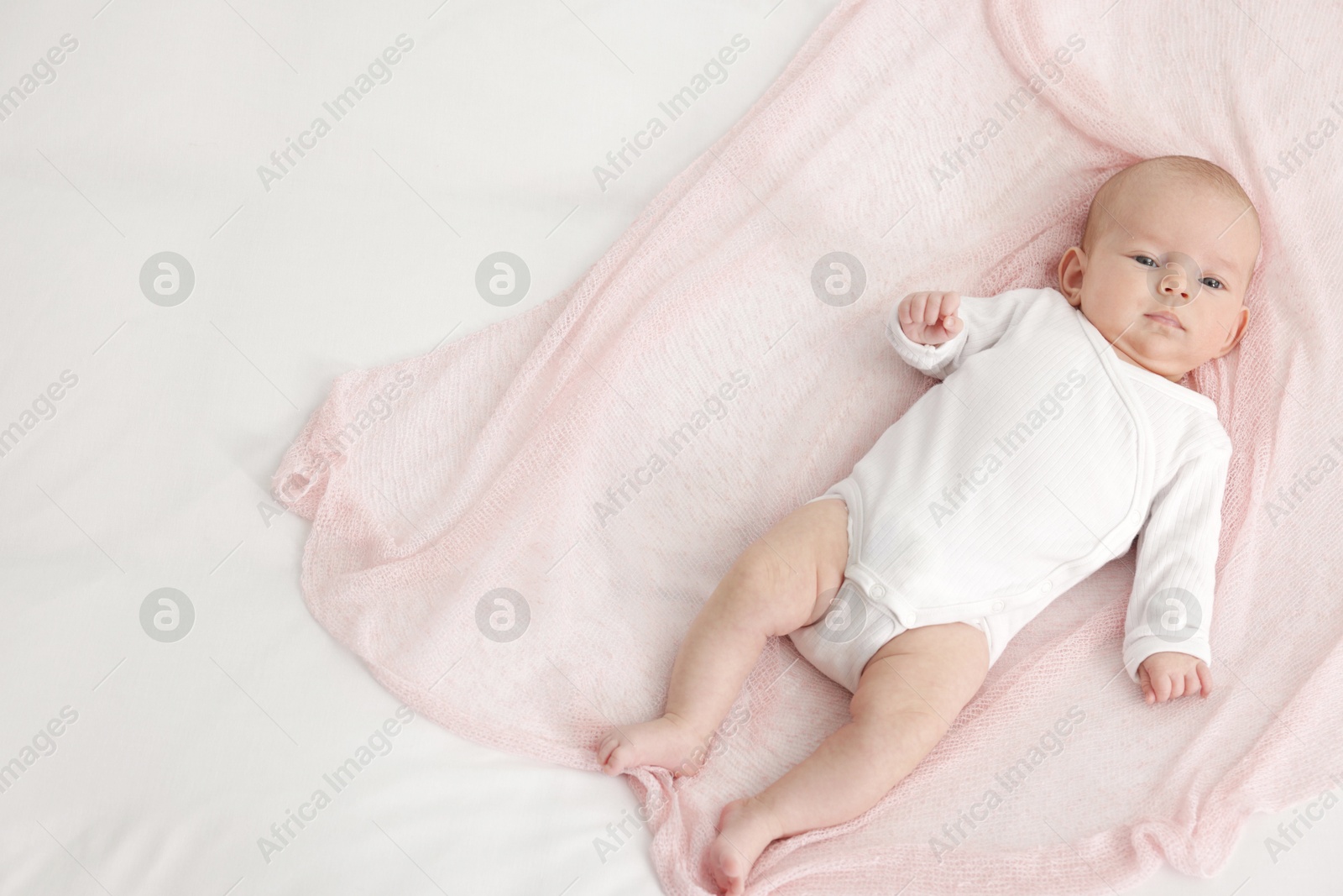 Cute little baby lying on bed at home, top view. Space for text Photo of Cute little baby lying on bed at home, top view. Space for text