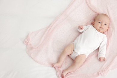 Photo of Cute little baby lying on bed at home, top view. Space for text