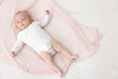 Photo of Cute little baby lying on bed at home, top view. Space for text