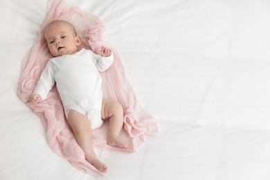 Photo of Cute little baby lying on bed at home, top view. Space for text