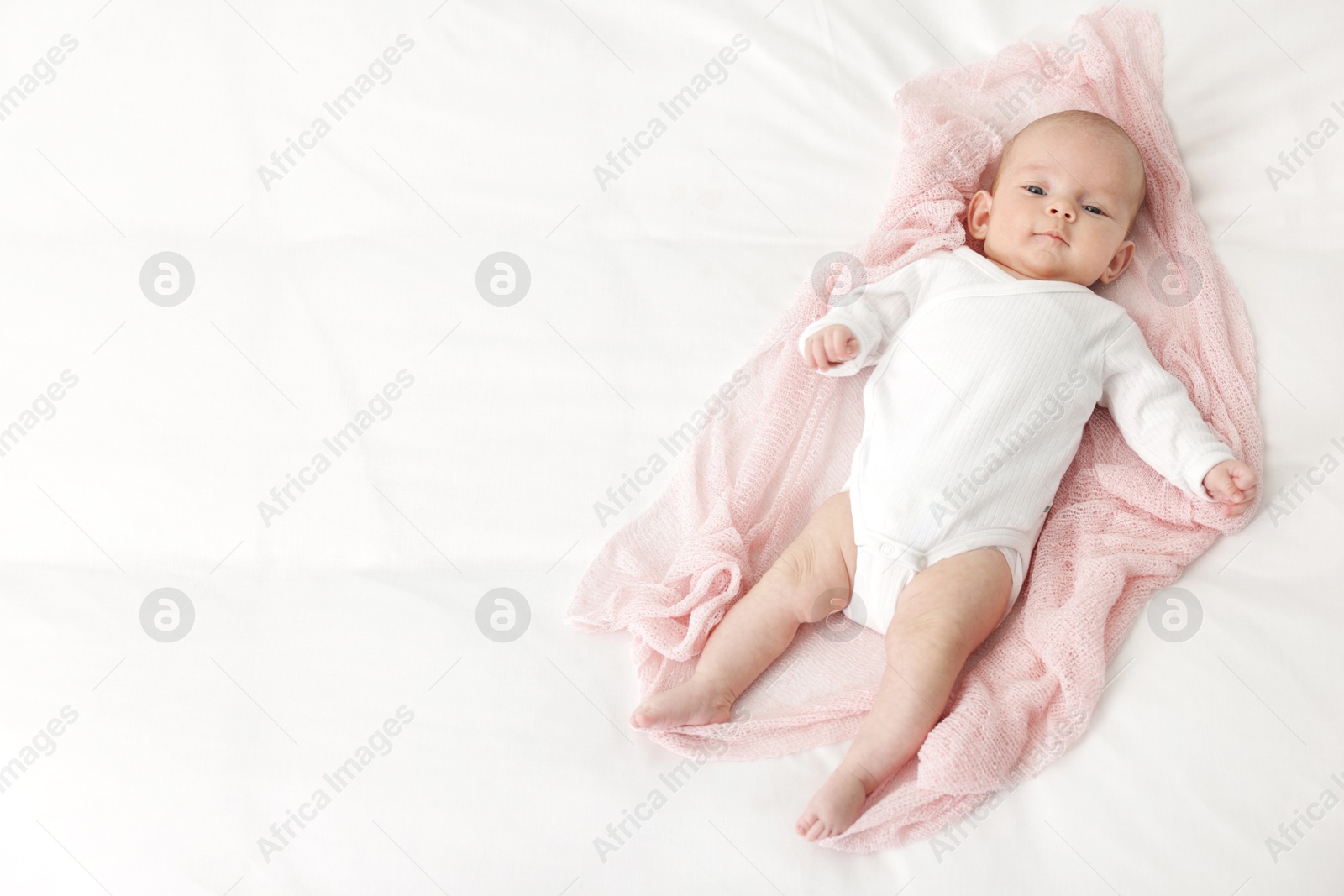Cute little baby lying on bed at home, top view. Space for text Photo of Cute little baby lying on bed at home, top view. Space for text