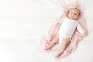 Photo of Cute little baby lying on bed at home, top view. Space for text