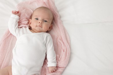 Photo of Cute little baby lying on bed at home, top view. Space for text