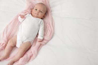 Photo of Cute little baby lying on bed at home, top view. Space for text