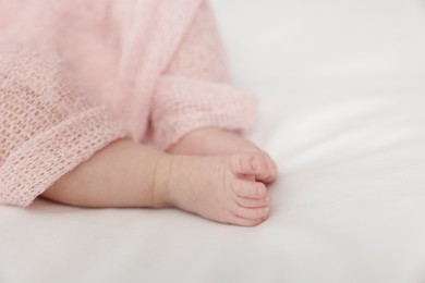 Photo of Cute little baby lying on bed at home, closeup. Space for text
