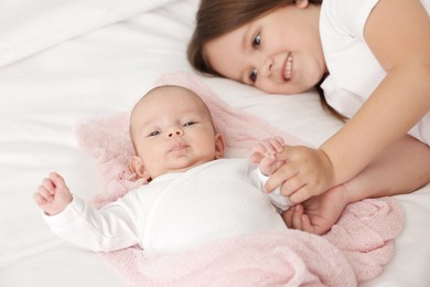 Photo of Cute girl and her little sister on bed at home, selective focus