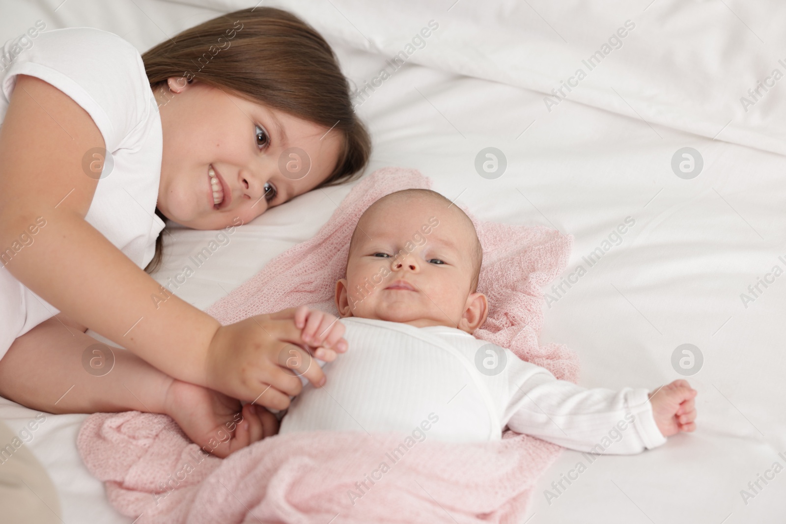 Cute girl and her little sister on bed at home, space for text Photo of Cute girl and her little sister on bed at home, space for text