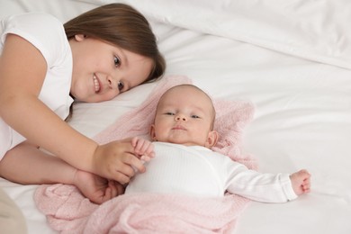 Photo of Cute girl and her little sister on bed at home, space for text