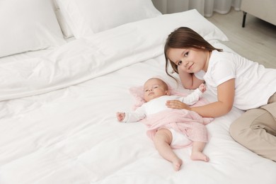 Photo of Cute girl and her little sister on bed at home, space for text