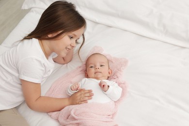 Photo of Cute girl and her little sister on bed at home, space for text
