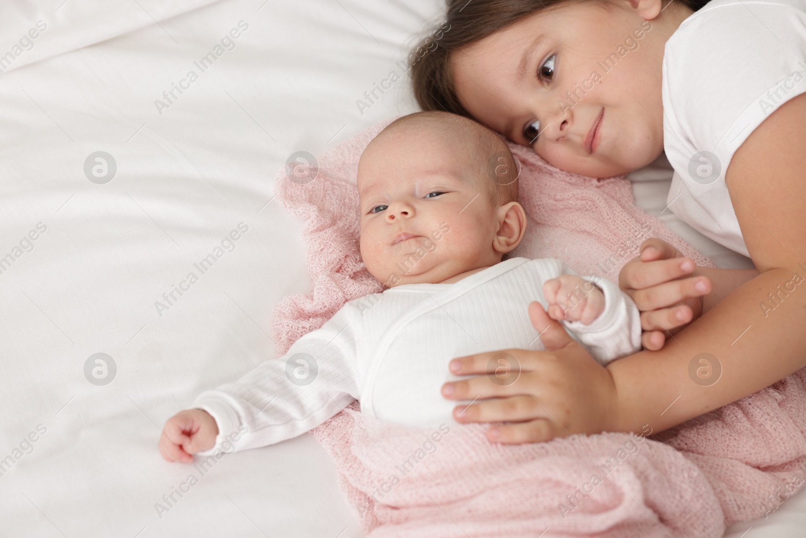 Cute girl and her little sister on bed at home, space for text Photo of Cute girl and her little sister on bed at home, space for text