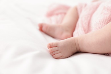 Photo of Cute little baby lying on bed at home, closeup. Space for text
